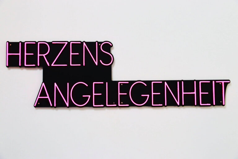 Neonschild mit Schriftzug "Herzensangelegenheit" an der Wand des Warteraums von Dr. Michaela Karner in Wiesen